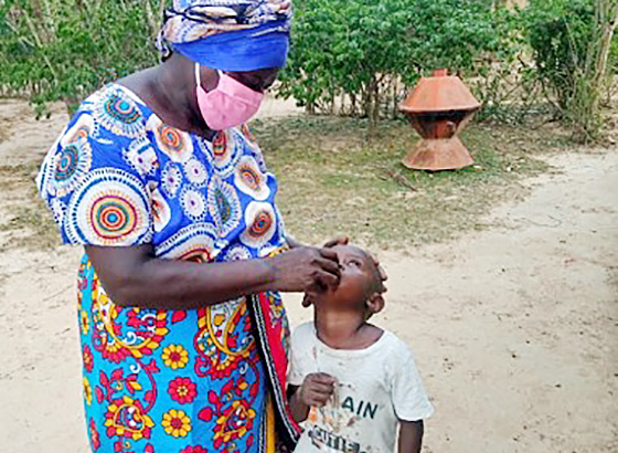A village health volunteers giving a vitamin A compound to a child during a household visit