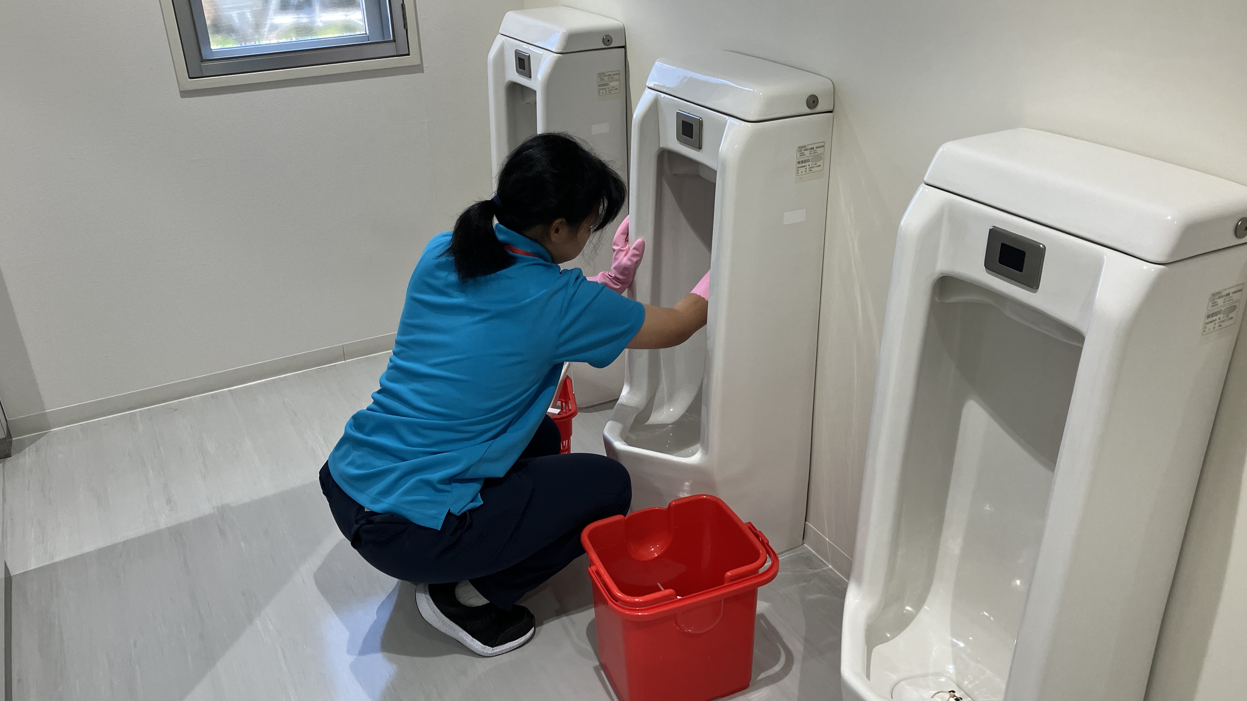 障がいのある方が男性トイレの小便器の清掃をしている写真です。