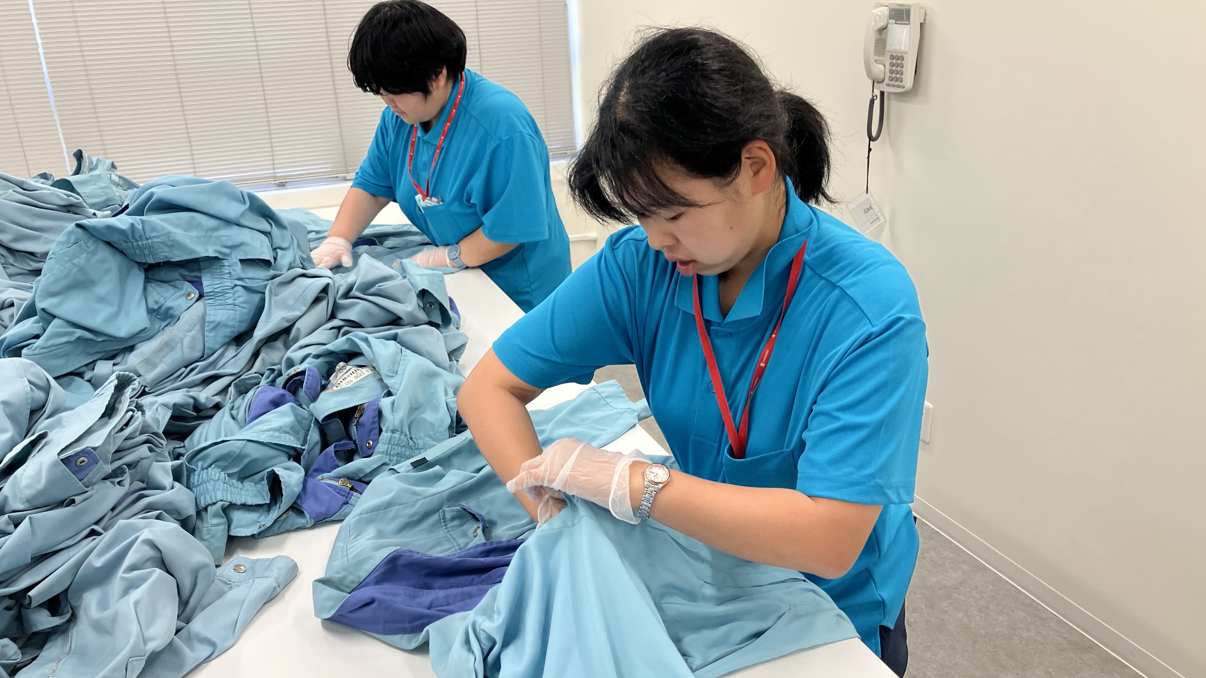 障がいのある方がテーブルの上で、ズボンの制服のポケットの中をチェックしている写真です。