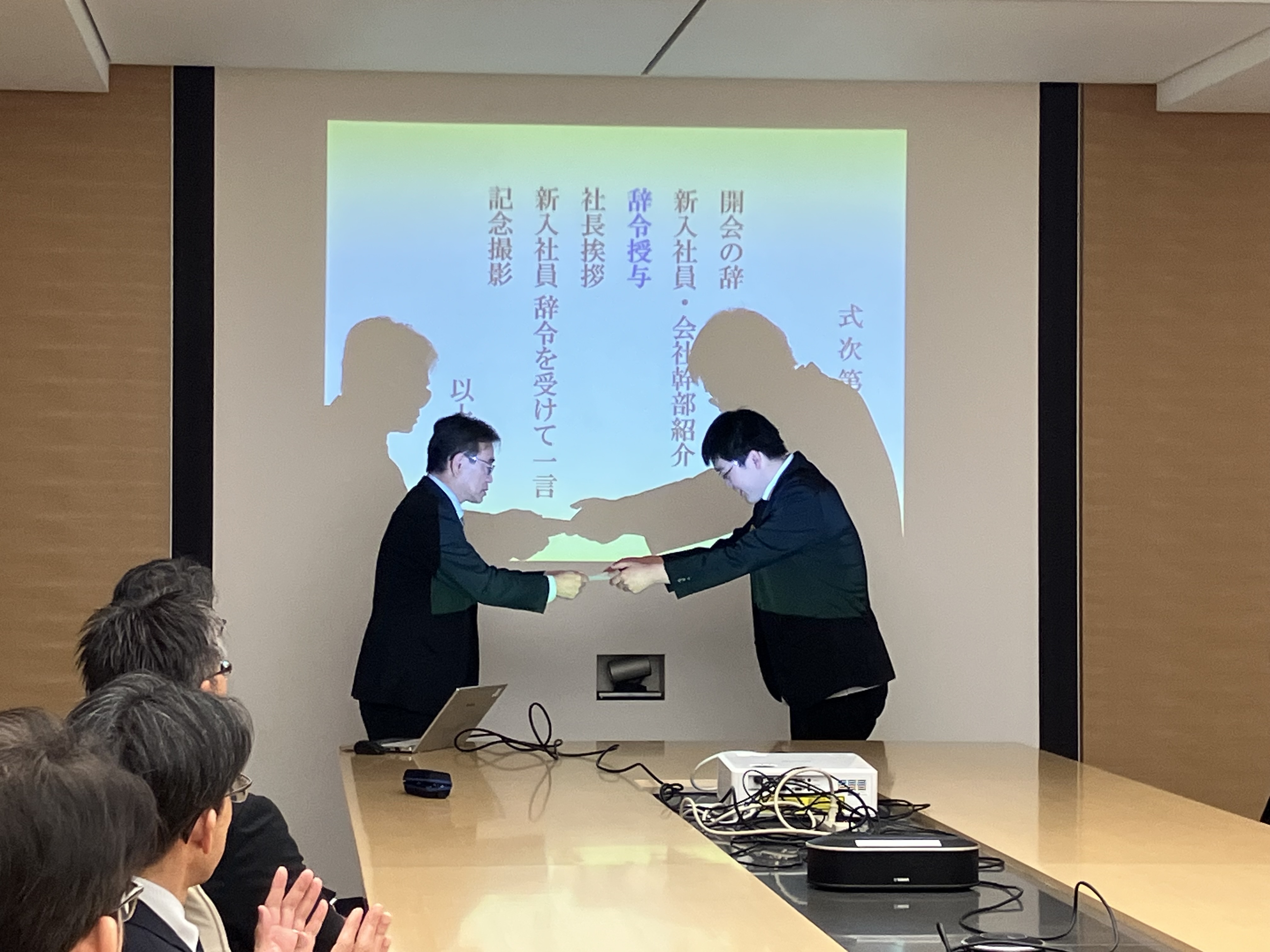 入社セレモニーで社長から辞令を受け取る従業員の写真